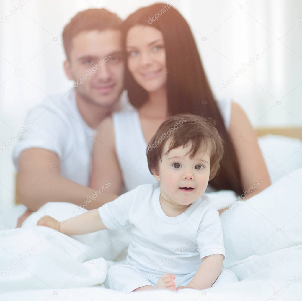 Portrait of a joyful family sitting on the bed at home