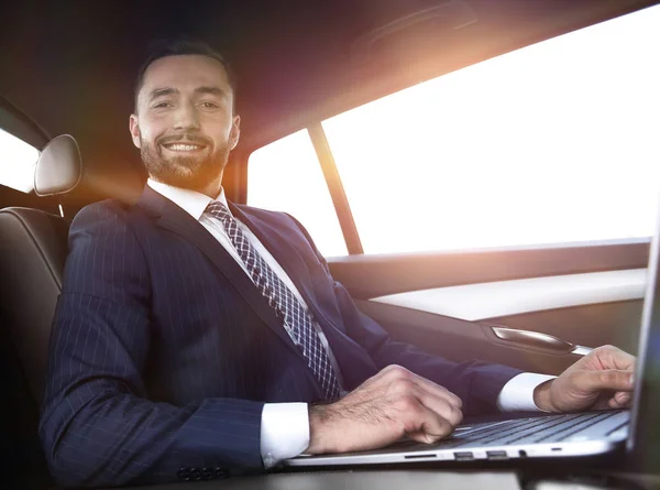 Hombre exitoso que trabaja con el ordenador portátil sentado en el coche —  Fotos de Stock