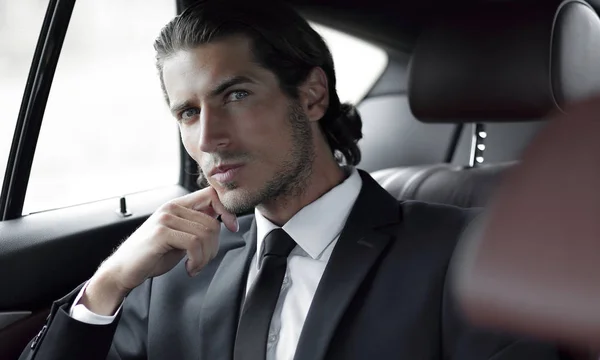 Successful man sitting in the back seat of a car — Stock Photo, Image