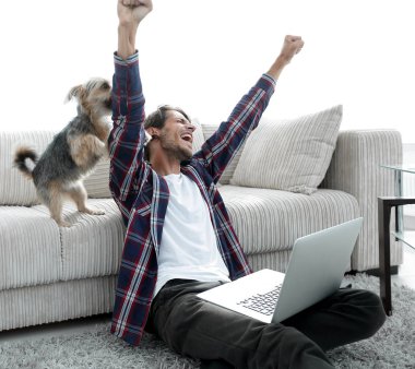 sevindirici ve yakın oturma odasında kanepede oturan ellerini yükselterek mutlu adam.