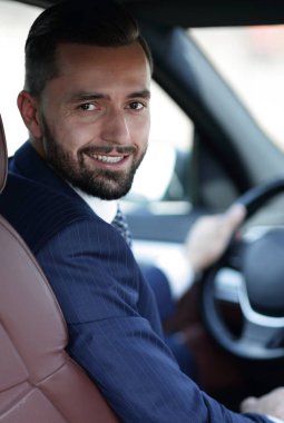 Kameraya bakarak bir arabanın ön koltuğunda otururken yakışıklı genç