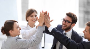 Başarılı bir iş ekibi ofiste birbirlerine beşlik çakıyor.