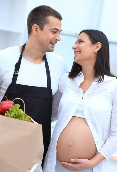 Kocası ve hamile karısını mutfakta ayakta paket ile penye — Stok fotoğraf