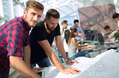 Yeni bir proje çizimlerini tartışırken iki Mimarlar