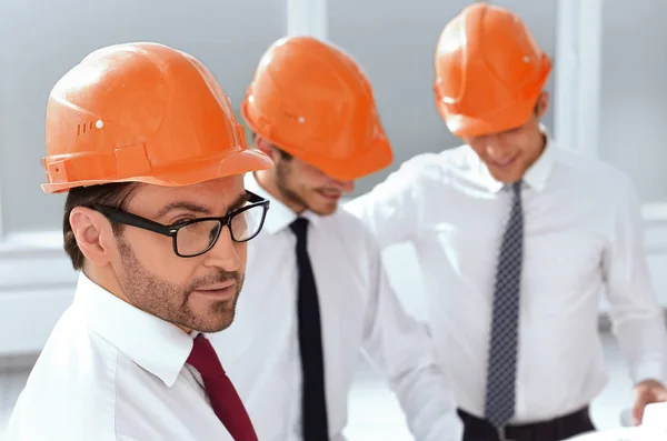 De cerca. un grupo de arquitectos de pie en la sala del nuevo edificio — Foto de Stock