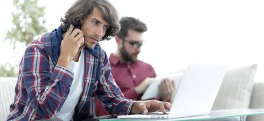 adam kanepede oturan, belgili tanımlık smartphone üzerinde konuşmak ve internette bilgi arayan bir arkadaşıyla.