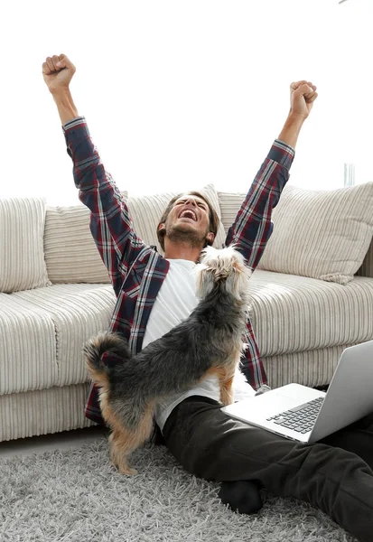 Mutlu genç adam köpeğiyle oturma odasında exults — Stok fotoğraf