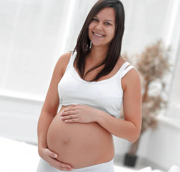 Portret van jonge zwangere vrouw op een lichte achtergrond. — Stockfoto