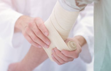 Doktor hasta dirsek üzerinde Elastik Bandaj uygulama.