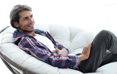 yakın çekim. gülümseyen adam büyük bir rahat sandalyede dinleniyor