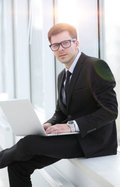 Genç profesyonel ofis pencere arka plan üzerinde dizüstü bilgisayar ile