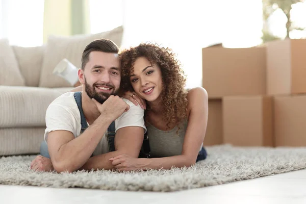 Happy couple lying on the carpet on the blurred background — Stock Photo, Image