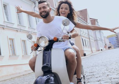 mutlu genç bir çift bir scooter üzerinde eğleniyor