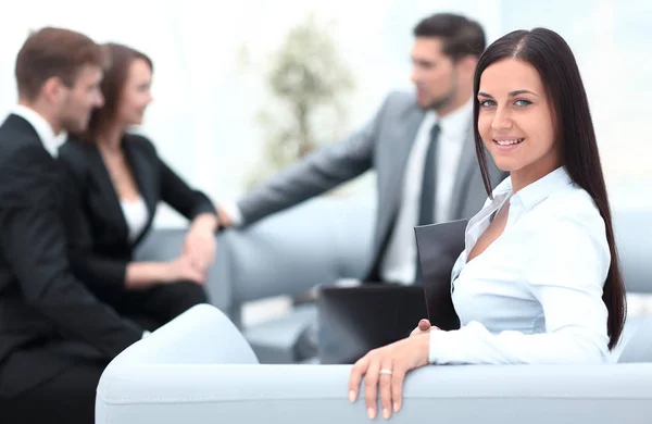 Giovane donna d'affari seduta in ufficio in background business team — Foto Stock