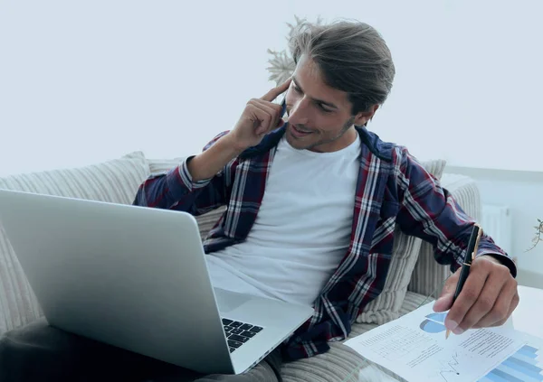 Joven discutiendo en un teléfono inteligente un gráfico financiero en casa . —  Fotos de Stock