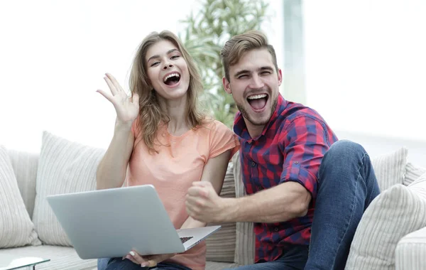 Jong koppel verheugt zich, zittend op de Bank tegenover de opengeklapte laptop — Stockfoto