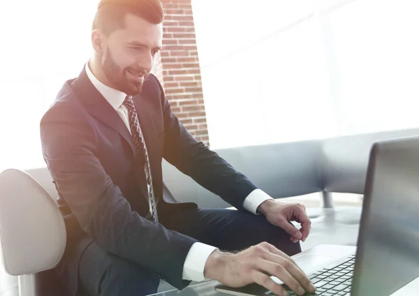 Uomo d'affari che lavora sul computer portatile seduto nella hall dell'ufficio — Foto Stock