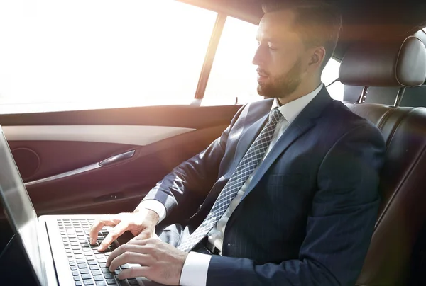 Uomo d'affari che lavora con il computer portatile seduto in auto — Foto Stock