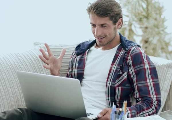 Glücklicher junger Mann, der von zu Hause aus mit Laptop arbeitet. — Stockfoto