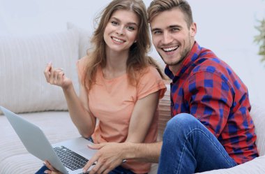 Dizüstü bilgisayarı olan iki öğrenci kanepede oturuyor.