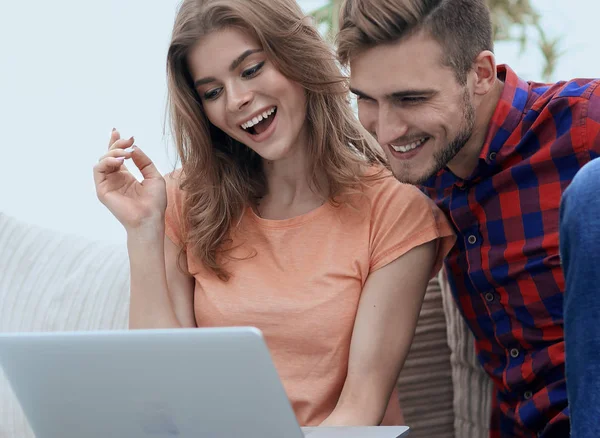 Young man with his girlfriend looking at the laptop sitting on t — Stock Photo, Image