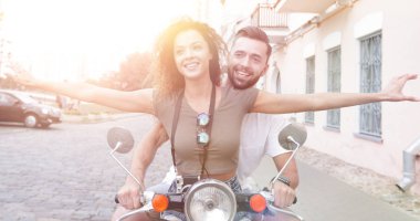 Güzel genç bir çift bir scooter sürme sırasında gülümsüyor