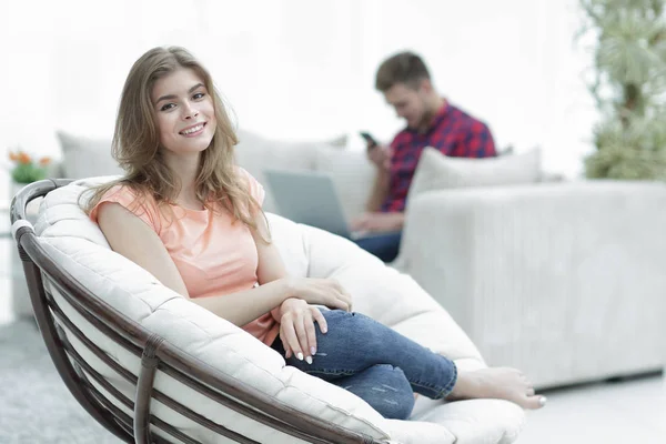 Beautiful young woman sitting in a large comfortable chair — Stock Photo, Image