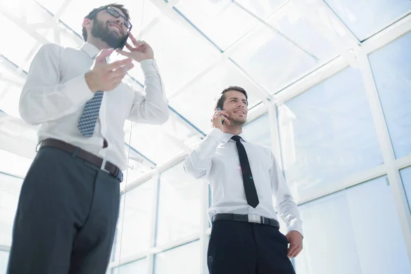 Abajo view.two empresarios exitosos hablando en sus teléfonos inteligentes . — Foto de Stock