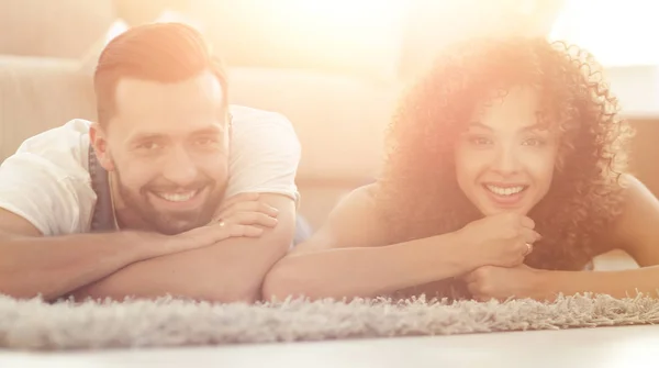 Young couple lying on the rug on the background of a new apartment — Stock Photo, Image