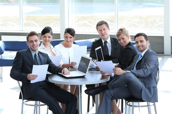 Groep van mensen uit het bedrijfsleven met de documenten zitten aan een tafel in de lobby van de Bank. — Stockfoto