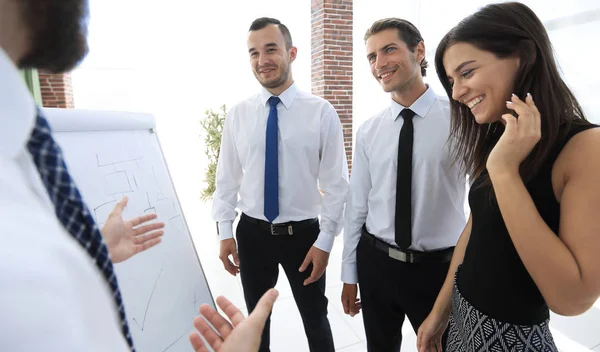 Geschäftsmann zeigt Geschäftsteam auf leeres Flipchart. — Stockfoto