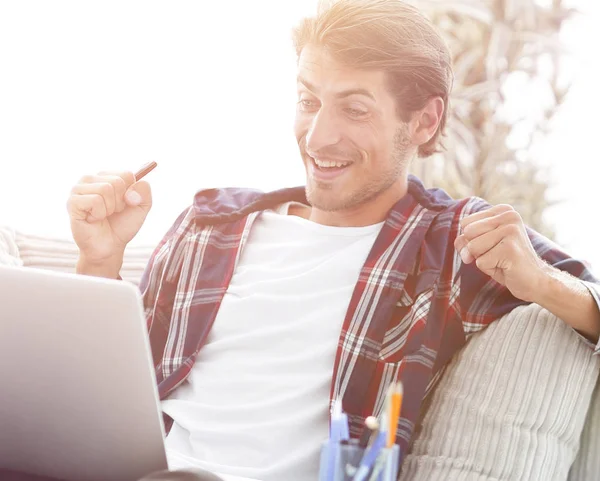 Glücklicher junger Mann, der von zu Hause aus mit Laptop arbeitet. — Stockfoto