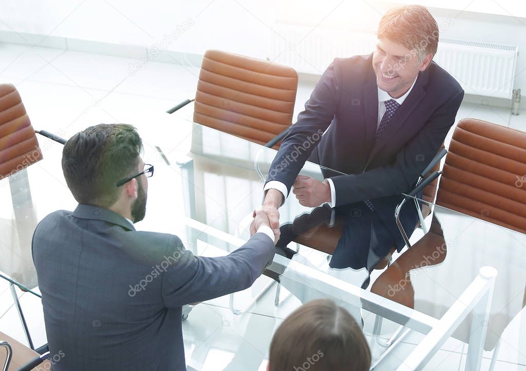 Handshake across the table of financial partners