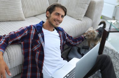 başarılı adam kanepede yakın katta oturan hayvanını okşayarak