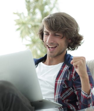 bir sehpa oturan bir dizüstü bilgisayar ile çok mutlu adam.