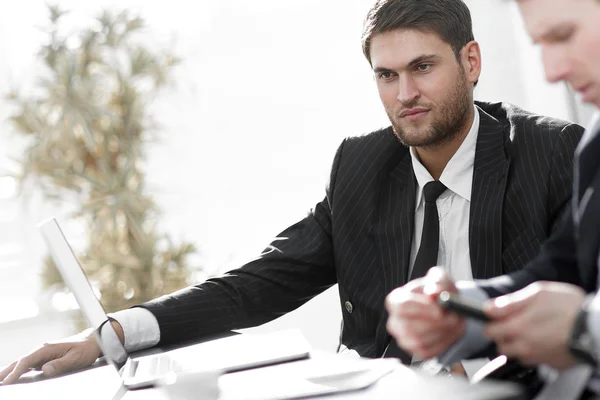 Exitoso hombre de negocios con su colega sentado detrás de un escritorio . — Foto de Stock