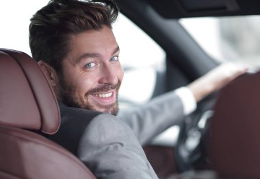 Dikiz aynası, genç adam arabasını sürüyor, kameraya bakıyor.