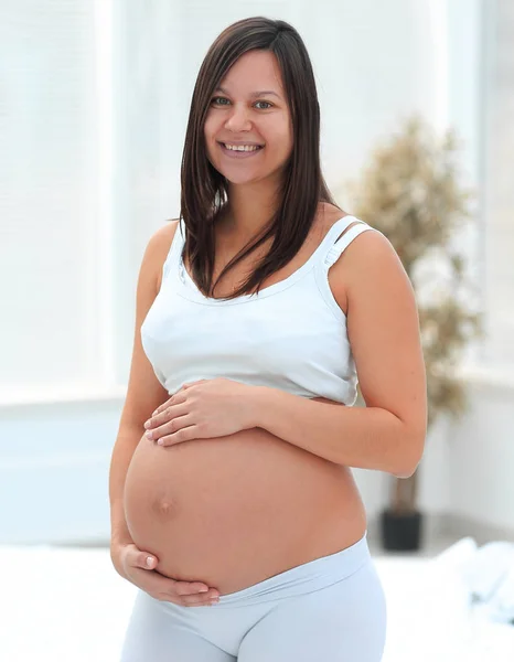 Portret van jonge zwangere vrouw op een lichte achtergrond. — Stockfoto