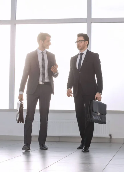 Muy lejos. dos hombres de negocios están caminando en el vestíbulo de la oficina —  Fotos de Stock