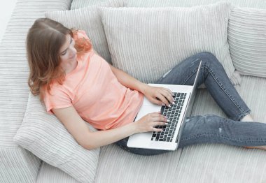 kız öğrenci dizüstü bilgisayar kanepede döşenmesi ile çalışma.