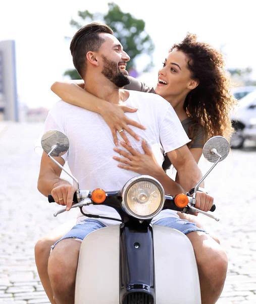 Heureux jeune couple chevauchant un scooter dans la ville par une journée ensoleillée — Photo