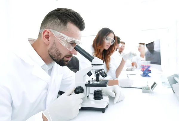 male lab technician looks at the sample under a microscope