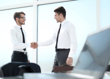 İki işadamı büyük pencerede el sıkışıyor.