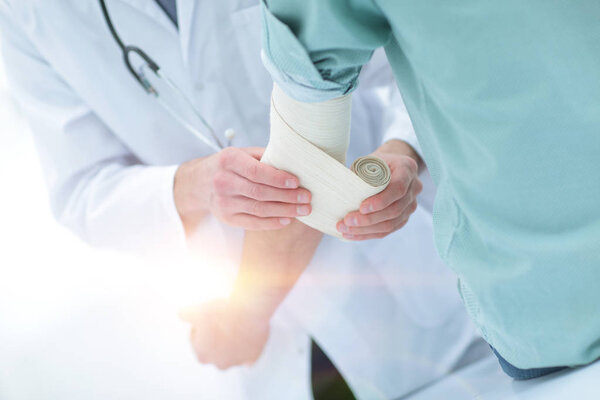 doctor applying elastic bandage on the elbow of the patient.