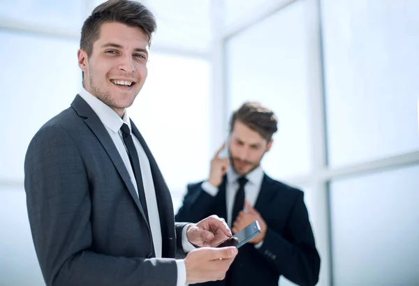 Imagen de un joven hombre de negocios usando un teléfono inteligente en el fondo de su —  Fotos de Stock