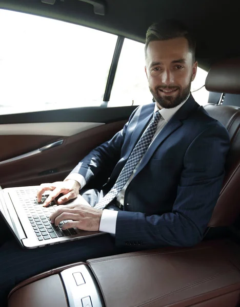 Fiatal üzletasszony dolgozik rajta laptop a kocsiban ülve — Stock Fotó