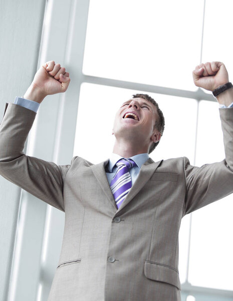 Shouting with joyful young entrepreneur raised hands.