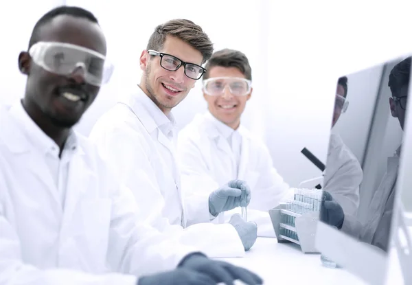 Groupe réussi de scientifiques assis à leur bureau — Photo