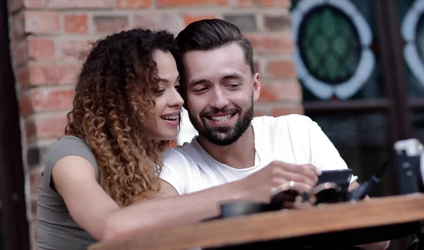 Счастливая влюбленная пара с помощью смартфона сидит на террасе — стоковое фото