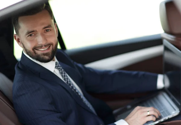 Confident businessman with laptop sitting in auto. — Stock Photo, Image